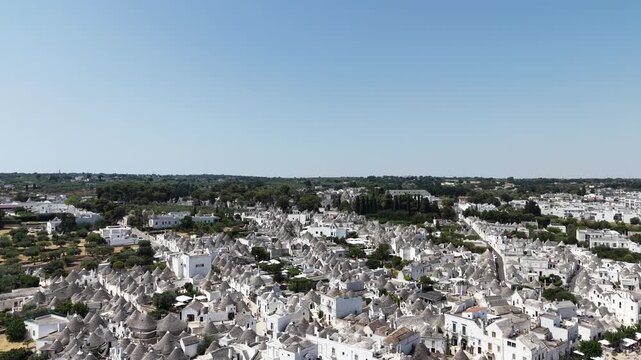 Scenic drone flight over the historic white trulli houses of alberobello, italy, a unesco world heritage site, revealing the unique conical rooftops in puglia