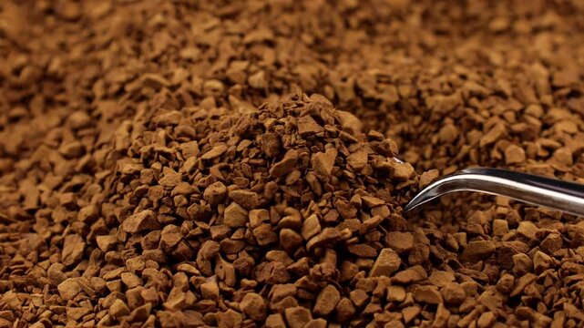 Brown instant freeze-dried coffee taking with a spoon close up