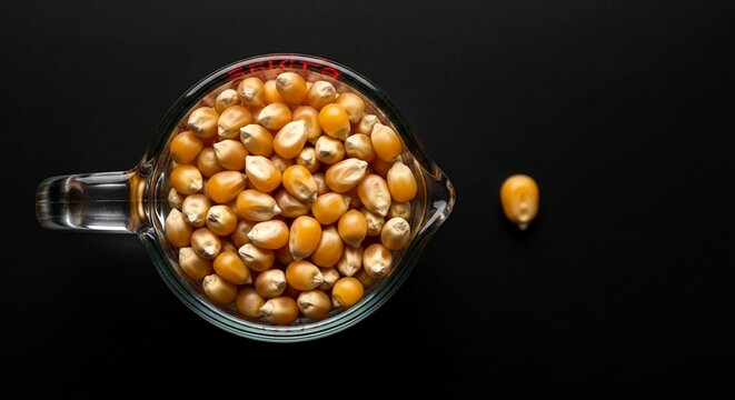 Yellow popcorn kernels in a clear measuring cup