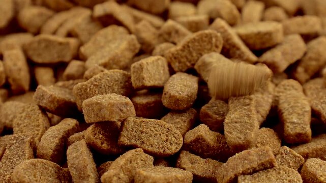 Brown kibble pieces of dry fish cat food falling down close up