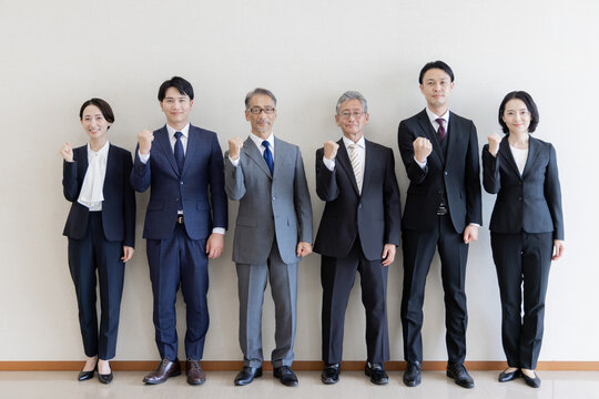 ガッツポーズで意気込みを見せる世代を超えたビジネスパーソンのグループ