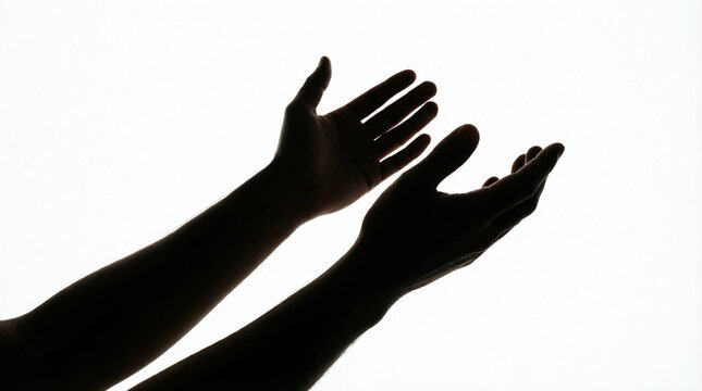 Silhouette of hands reaching upward in gesture of prayer or supplication against bright background