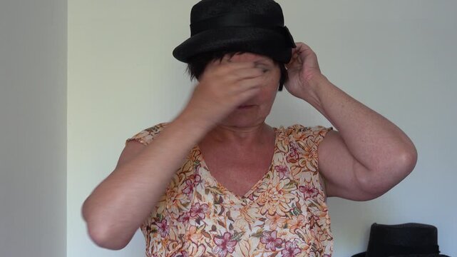 Woman adjusts her retro hat in a light room