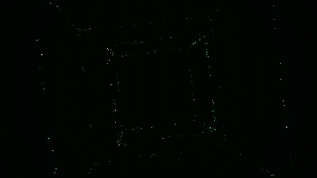 Green glowing geometric particles form a rotating wireframe cube structure inside a dark empty void space