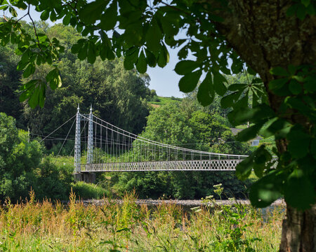 Victoria Bridge over the flowing River Spey near Aberlour in Moray Scotland during a bright summer day with lush green trees framing the view