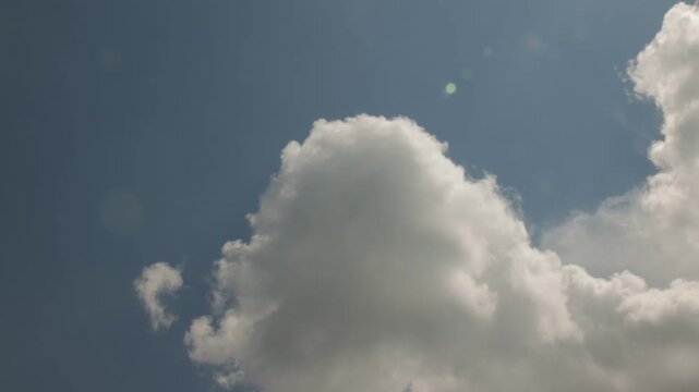 Timelapse of white and gray clouds moving across blue sky with wispy cloud layers