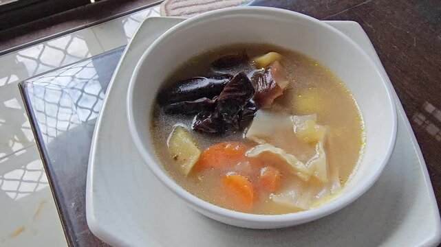 beef stew with vegetables,The bird nest soup,Indonesian called Sup sarang burung walet made from The Swiftlet nest,healthy food from Chinese tradition.Warm soup with vegetables in a white bowl. 