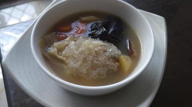 soup with rice,The bird nest soup,Indonesian called Sup sarang burung walet made from The Swiftlet nest,healthy food from Chinese tradition.Warm soup with vegetables in a white bowl. Soft light 