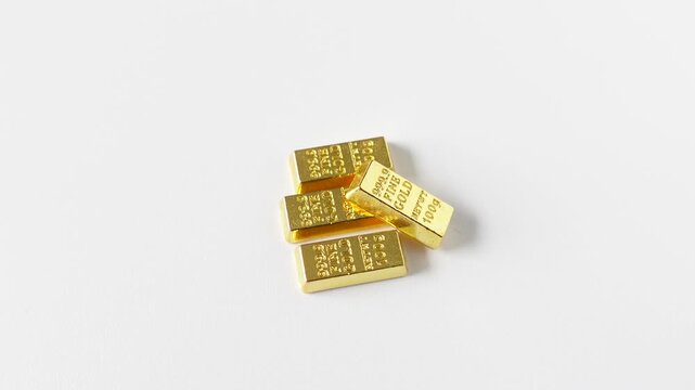 Top view of a miniature gold bars imitation engraved with 999.9 Fine Gold and 100g spinning on a white background