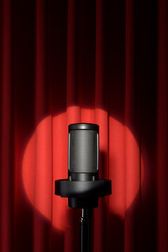 Microphone with spotlight on red stage curtain.