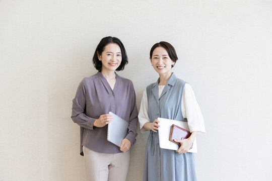 ノートパソコンを抱える笑顔のビジネスウーマン2人のポートレート