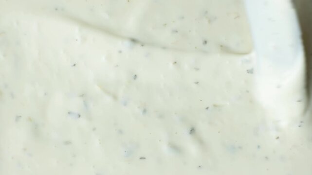 Top view of a knife smoothing creamy tartar sauce texture