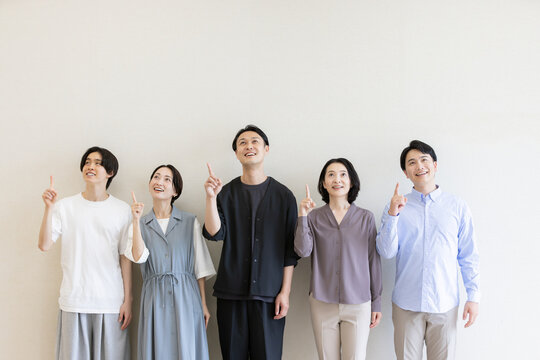 上を指差して未来やアイデアを示す日本人男女のグループ