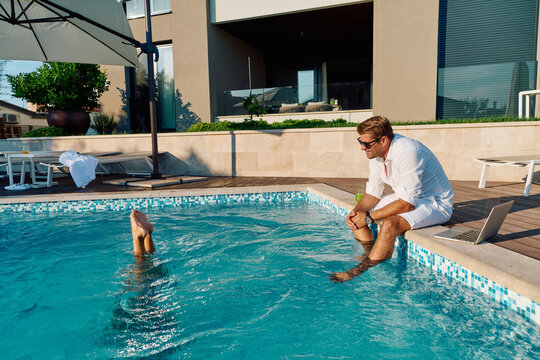 Relaxing Man With Laptop at Luxury Home Poolside on Sunny Summer Morning