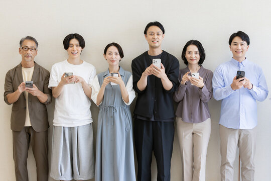 スマートフォンを操作する多世代の日本人グループポートレート