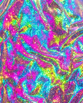 Holographic iridescent foil texture with vibrant rainbow sheen and glittering sparkle forming abstract crumpled metallic surface in pink cyan and gold tones.