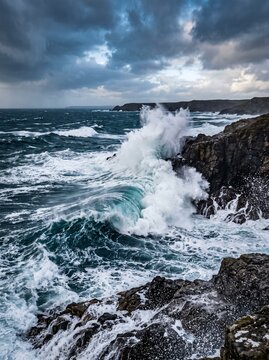 Powerful ocean waves crashing against rocky coastline under stormy skies