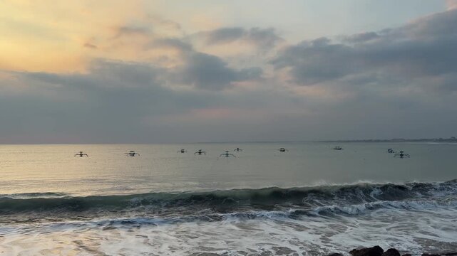 A serene seascape at sunset with gentle waves and fishing boats on the horizon. The sky is filled with soft clouds and warm colors.