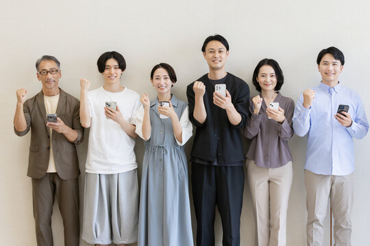 スマートフォンを持ちガッツポーズをする多世代の日本人グループスマートフォン, ガッツポーズ, 日本人