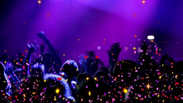 Crowd members dance with raised arms under bright purple stage lights and falling confetti pieces.