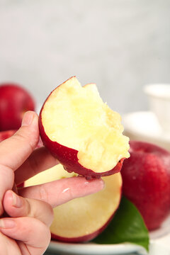 Fresh Red Apple Bite - Hand Holding Crisp Fruit Slice with Natural White Flesh