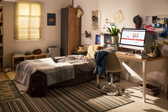 Wide angle shot of teenager bedroom workspace featuring desktop computer and laptop, supporting studying and remote learning. Ideal for education, student life, home office marketing