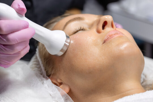 Close-up of a cosmetic physician performing radio frequency facial treatment to improve skin firmness, stimulate collagen production and rejuvenate the face in a beauty clinic.