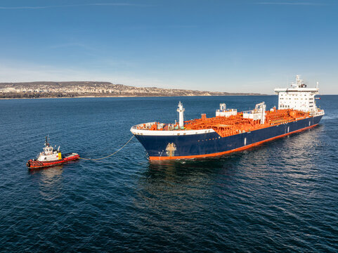 Large oil tanker ship escorted by two tugboats. Concept of maritime transport, global logistics, and international trade.