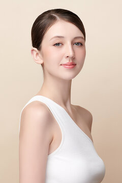 A beautiful young Asian woman with clean, fresh skin against a beige background. Skincare, facial treatment, cosmetology, beauty, and spa. An elegant portrait of an Asian woman.