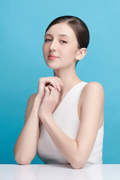 A beautiful young Asian woman with clean, fresh skin against a blue background. Skincare, facial treatment, cosmetology, beauty, and spa. An elegant portrait of an Asian woman.