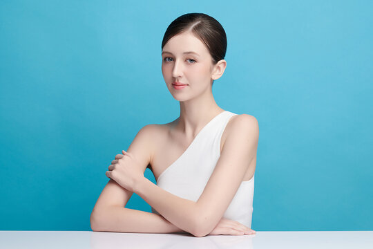 A beautiful young Asian woman with clean, fresh skin against a blue background. Skincare, facial treatment, cosmetology, beauty, and spa. An elegant portrait of an Asian woman.
