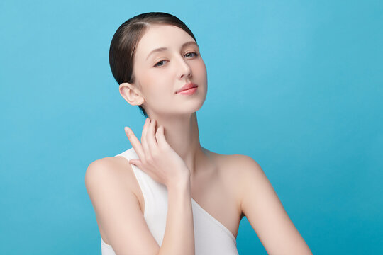 A beautiful young Asian woman with clean, fresh skin against a blue background. Skincare, facial treatment, cosmetology, beauty, and spa. An elegant portrait of an Asian woman.