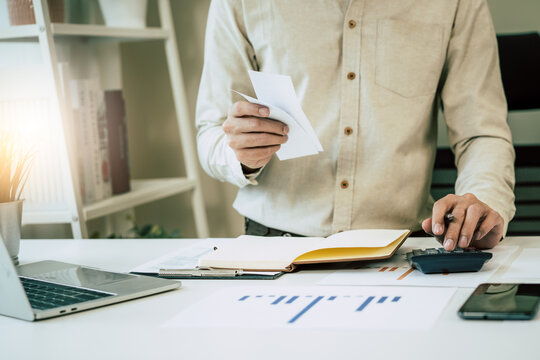 Deduction planning, debt asian accountant hand using calculator to calculating money balance from bill and income, cost budget expenses for pay money form personal individual on table at home.
