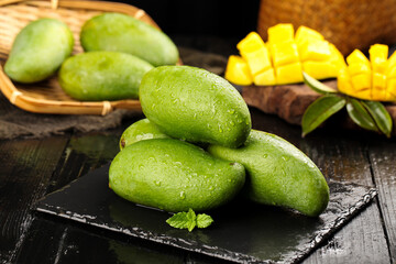 Fresh Green Mangoes from Vietnam on Rustic Wood Background with Tropical Fruit Display © LamHuong
