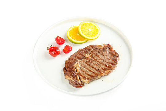 Grilled Beef Steak with Lemon and Tomatoes on White Plate - Restaurant Food Presentation