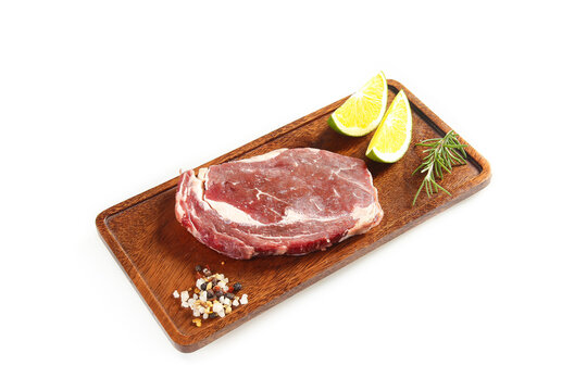 Fresh Raw Ribeye Beef Steak on Wooden Board with Lime and Herbs