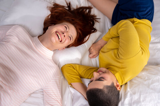Happy Lesbian Couple Lying on Bed Together and Laughing