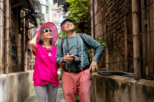 Happy Senior Asian Couple Traveling Together in Urban Alley