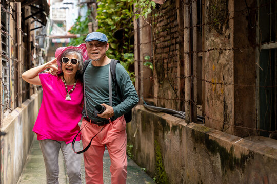 Happy Senior Asian Couple Traveling Together in Urban Alley