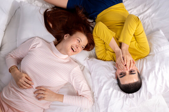 Happy Lesbian Couple Lying on Bed Together and Laughing
