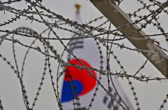 Fence and flag at the Korean Demilitarized Zone is a strip of land running across the Korean Peninsula that serves as a buffer zone between North & South Korea which runs along the 38th parallel north