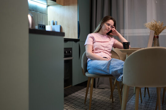 Female resting at kitchen table near laptop indoors