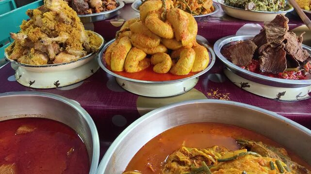 A colorful display of Nasi Kapau dishes at a local food stall. The assortment includes Gulai Tambusu, rendang, vegetables cooked in coconut milk curry, and other Minangkabau specialties.