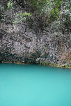 Turquoise pool and rocky forest cliff at Libo Small Seven Holes Scenic Area, Guizhou
