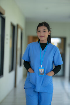 Senior care scene: Young Asian nurse in blue scrubs writing patient notes on a tablet at the bedside of an elderly man recovering in a hospital ward, warm caring atmosphere