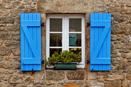 Blue shutters on a historic stone house in Brittany
