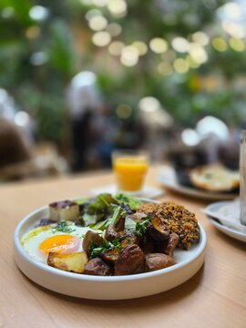 Healthy brunch plate with a baked egg and mushrooms in a plant-filled cafe