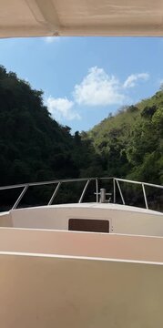 A boat navigating through a lush green canyon under a clear blue sky. The scene captures the tranquility of nature and the beauty of outdoor adventures.