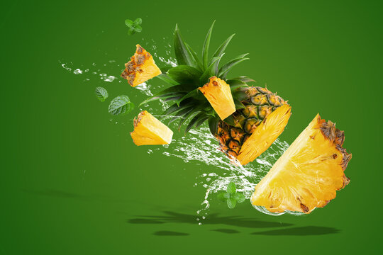 Fresh whole pineapple and slices splashing into water with green background. Water Splashing on Fresh Pineapple is tropical fruit isolated on Green background. space for text.