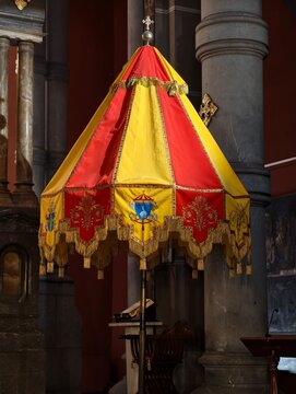 Palio ceremonial rojo y amarillo con escudos her&aacute;ldicos en el interior de una iglesia